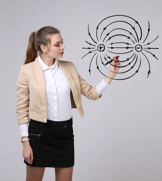 Jeune femme, professeur de physique dessine un diagramme du champ électrique — Photo