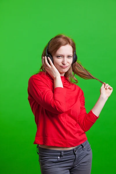 Woman listening music on headphones, green background — Stock Photo, Image