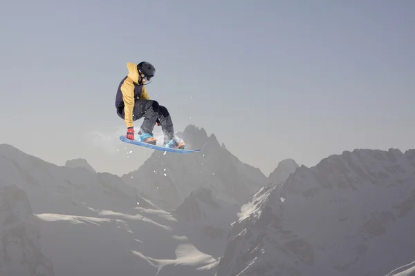 Καβαλάρης snowboard πηδάει στα βουνά. Extreme snowboard ελεύθερο άθλημα. — Φωτογραφία Αρχείου