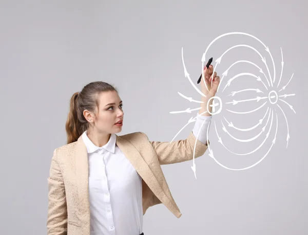 Giovane donna, insegnante di fisica disegna un diagramma del campo elettrico — Foto Stock