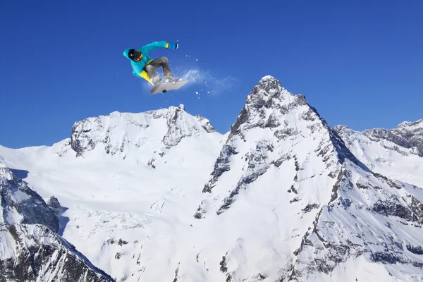 Cavaleiro de snowboard pulando em montanhas. Esporte de freeride de snowboard extremo. — Fotografia de Stock