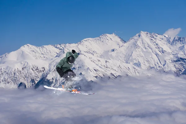 Cavaleiro de esqui pulando em montanhas nevadas. Esporte de freeride de esqui extremo . — Fotografia de Stock