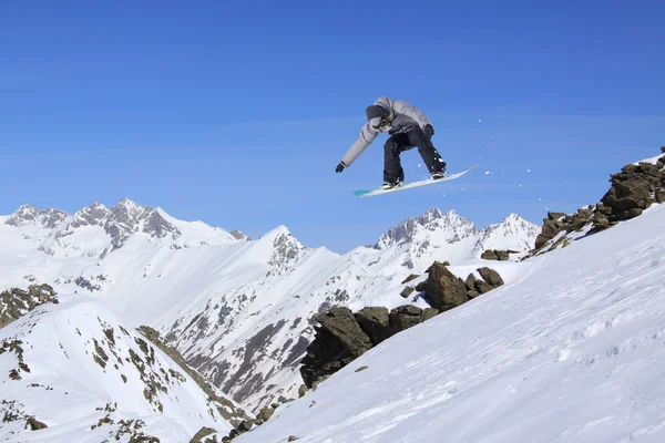 スノーボードライダー冬の山々にジャンプします。極端なスノーボードフリーライドスポーツ. — ストック写真