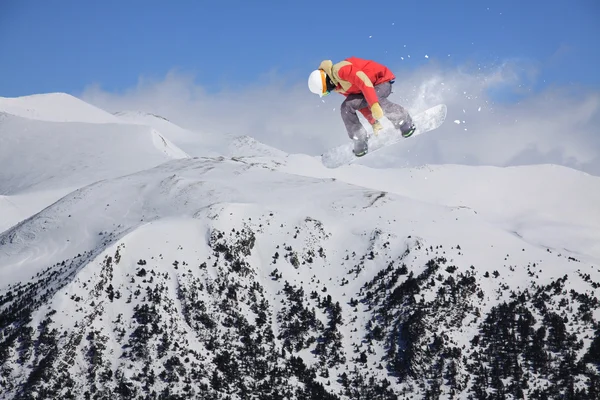 Cavaleiro de snowboard pulando em montanhas. Esporte de freeride de snowboard extremo. — Fotografia de Stock