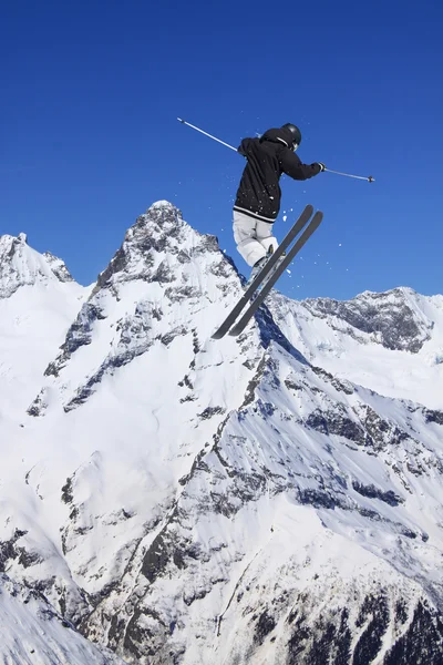 Lyžařské jezdec skákat na horách. Extrémní lyžařské freeride sport. — Stock fotografie