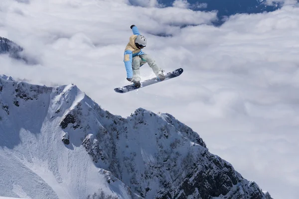 Cavaleiro de snowboard pulando em montanhas. Esporte de freeride de snowboard extremo. — Fotografia de Stock