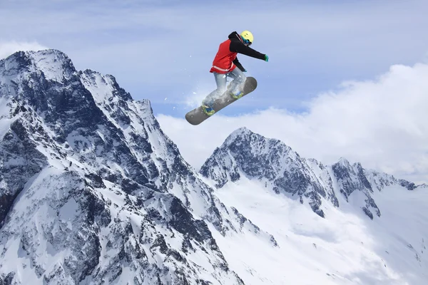 Cavaleiro de snowboard pulando em montanhas. Esporte de freeride de snowboard extremo. — Fotografia de Stock