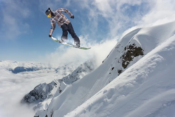 Cavaleiro de snowboard pulando em montanhas. Esporte de freeride de snowboard extremo. — Fotografia de Stock