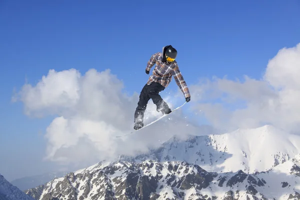 Cavaleiro de snowboard pulando em montanhas. Esporte de freeride de snowboard extremo. — Fotografia de Stock