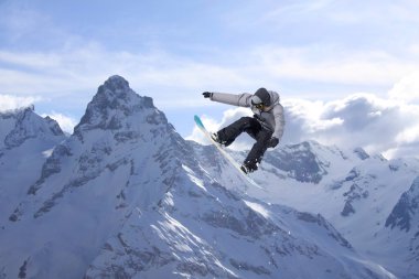 Dağlarda atlayan snowboard binicisi. Ekstrem snowboard serbest spor.