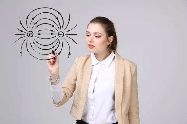 Mujer joven, profesora de física dibuja un diagrama del campo eléctrico — Foto de Stock