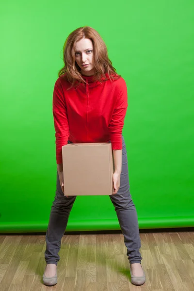 Mujer sosteniendo caja de cartón sobre fondo verde — Foto de Stock