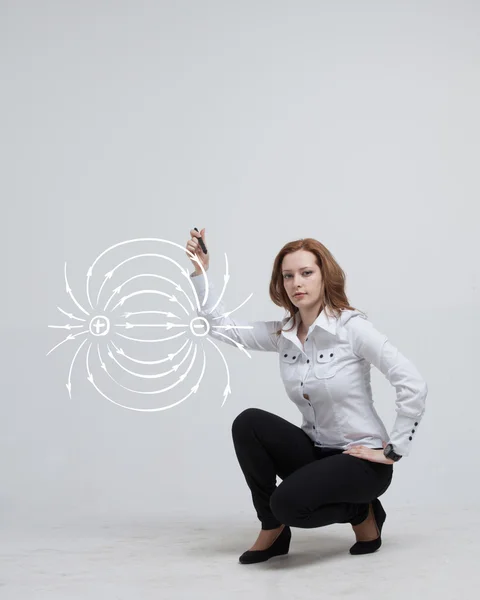 Jonge vrouw, natuurkunde leraar trekt een diagram van het elektrisch veld — Stockfoto