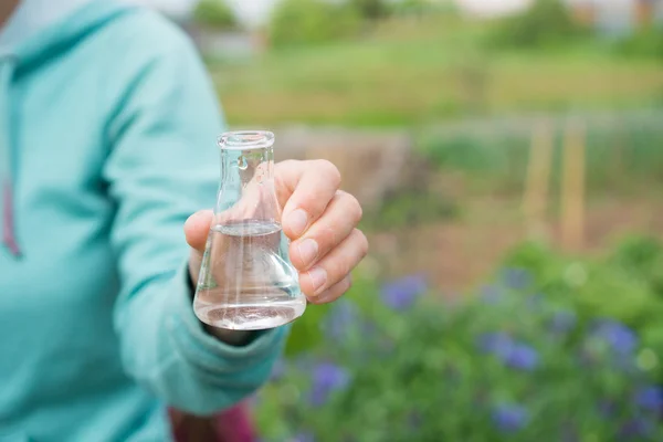 Mano con provetta e pianta. Fertilizzante in vetreria da laboratorio . — Foto Stock