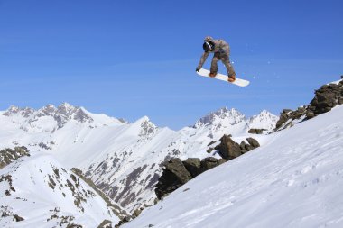 Dağlarda atlayan snowboard binicisi. Ekstrem snowboard serbest spor.