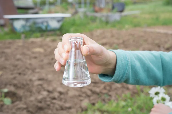 Main avec une éprouvette et une plante. Engrais en verrerie de laboratoire . — Photo