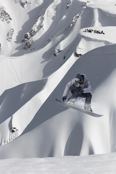 Cavaleiro de snowboard pulando em montanhas. Esporte de freeride de snowboard extremo. — Fotografia de Stock