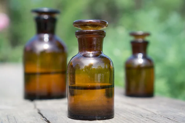 Pequeñas botellas marrones en tablero de madera y hierba verde — Foto de Stock