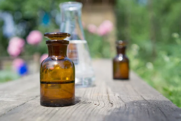 Flüssigkeit in chemischem Geschirr auf dem Hintergrund von Pflanzen, Düngemitteln oder Pestiziden im Garten. — Stockfoto