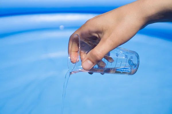 Pruebas de agua en la piscina, cristalería de laboratorio en la mano — Foto de Stock