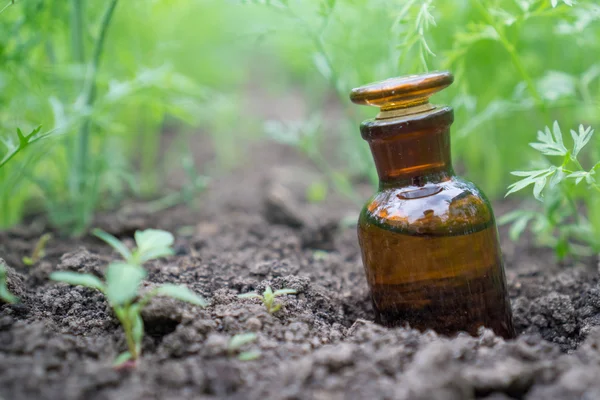 Vloeistof in chemische ware op een achtergrond van planten, meststoffen en pesticiden in de tuin. — Stockfoto