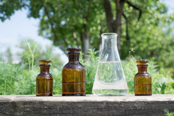 Vätska i kemiska ware på en bakgrund av växter, gödselmedel och bekämpningsmedel i trädgården. — Stockfoto