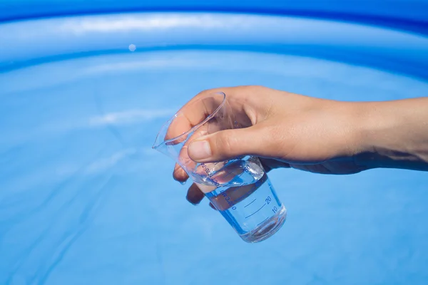 Pruebas de agua en la piscina, cristalería de laboratorio en la mano — Foto de Stock