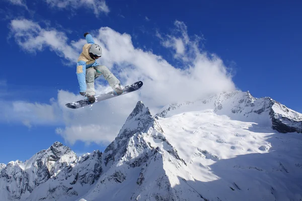 Cavaleiro de snowboard pulando em montanhas. Esporte de freeride de snowboard extremo. — Fotografia de Stock