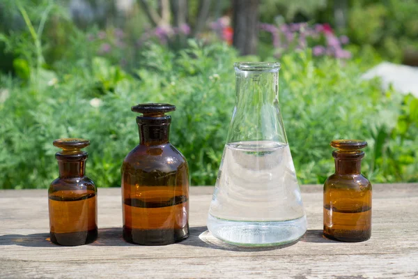 Vloeistof in chemische ware op een achtergrond van planten, meststoffen en pesticiden in de tuin. — Stockfoto