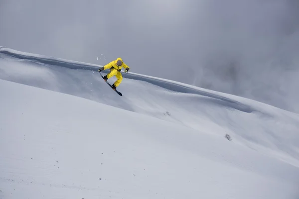 Jeździec na snowboardzie skaczący po górach. Ekstremalne snowboard freeride sportu. — Zdjęcie stockowe