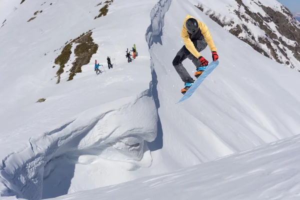 Cavaleiro de snowboard pulando em montanhas. Esporte de freeride de snowboard extremo. — Fotografia de Stock