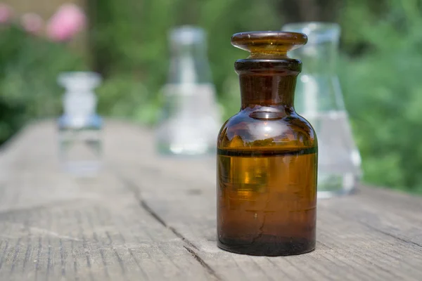 Vloeistof in chemische ware op een achtergrond van planten, meststoffen en pesticiden in de tuin. — Stockfoto