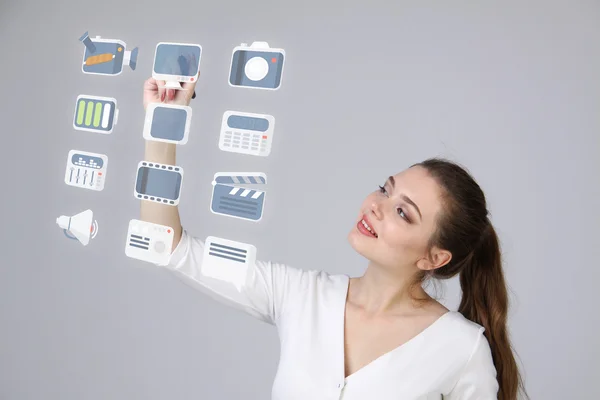 Vrouw op multimedia- en entertainmentoplossing pictogrammen op een virtuele achtergrond te drukken — Stockfoto