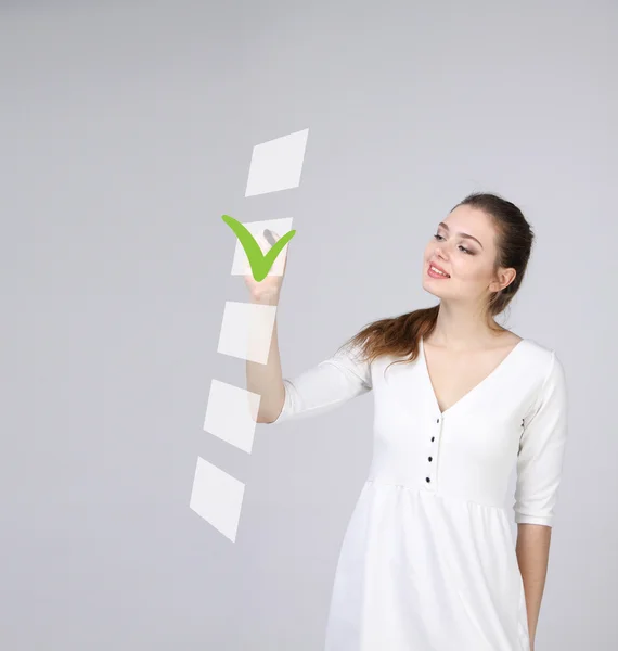 Junge Geschäftsfrau beim Ankreuzen der Checkliste. grauer Hintergrund. — Stockfoto