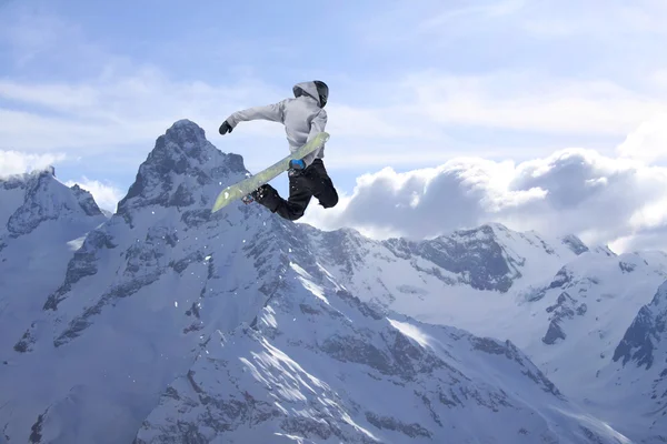 Snowboarder springt hoog in de bergen. — Stockfoto