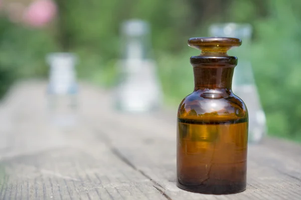 Flüssigkeit in chemischem Geschirr auf dem Hintergrund von Pflanzen, Düngemitteln oder Pestiziden im Garten. — Stockfoto