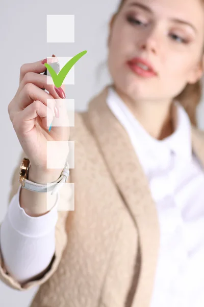 Junge Geschäftsfrau beim Ankreuzen der Checkliste. grauer Hintergrund. — Stockfoto