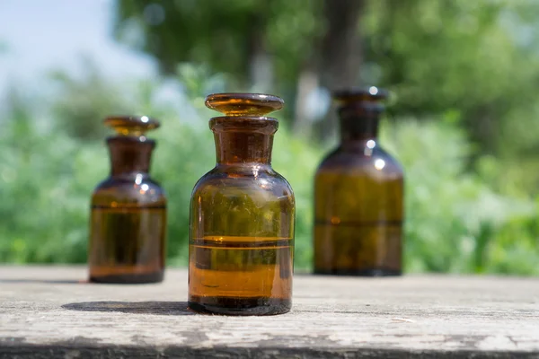 Pequeñas botellas marrones en tablero de madera y hierba verde — Foto de Stock