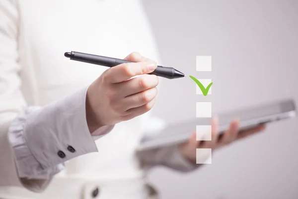 Young business woman checking on checklist box. Gray background. — Stock Photo, Image