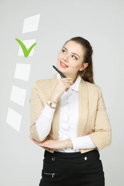 Junge Geschäftsfrau beim Ankreuzen der Checkliste. grauer Hintergrund. — Stockfoto