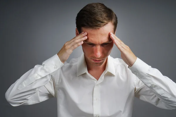 Young man in white shirt thinking or experiencing headaches. — Stock Photo, Image