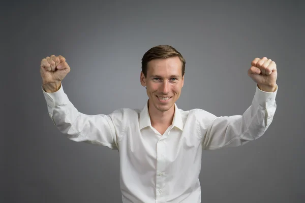 Un geste de succès. Homme souriant en chemise blanche aux mains levées . — Photo