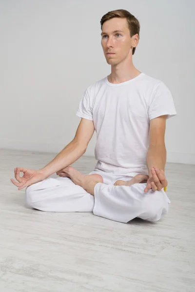 Giovane uomo che medita in posizione Lotus sul pavimento — Foto Stock