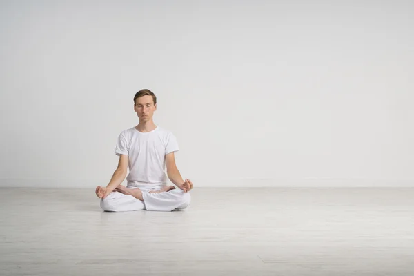 Young man meditating in Lotus position on the floor