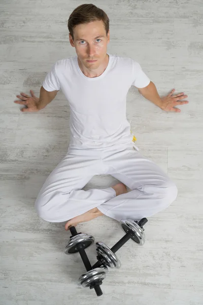 Un hombre sentado en el suelo con pesas. Tiempo de descanso . — Foto de Stock