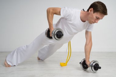 Genç adam dumbbells ile egzersiz yaparak.