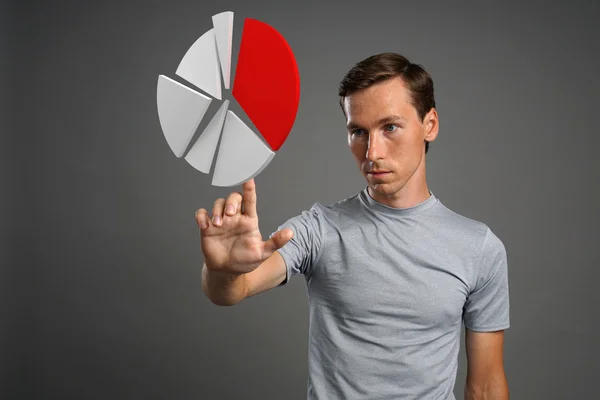 Hombre con camiseta trabajando con gráfico circular sobre fondo gris . — Foto de Stock