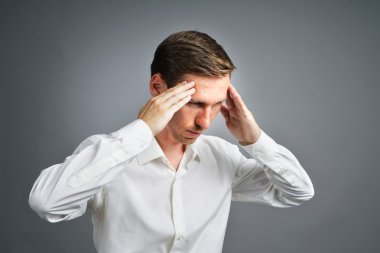 Young man in white shirt thinking or experiencing headaches.