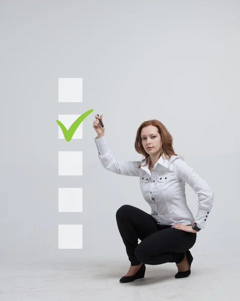 Ung affärskvinna kontroll på checklista låda. Grå bakgrund. — Stockfoto