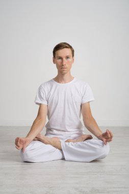 Genç adam yerdeki Lotus pozisyonda meditasyon